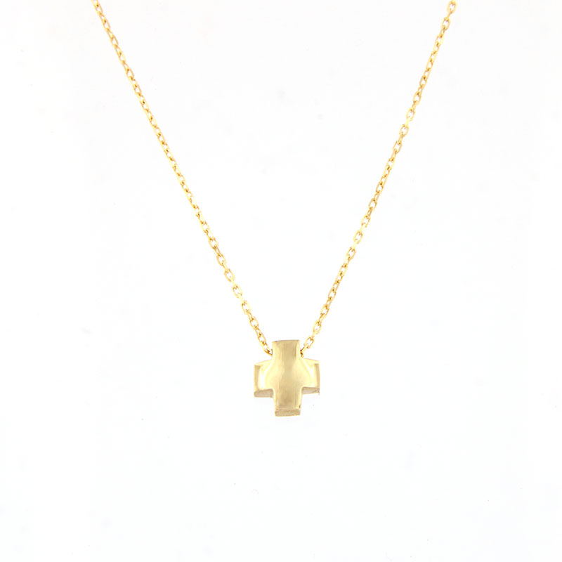 Womens small cross made of yellow gold with 14K chain on a patent surface.